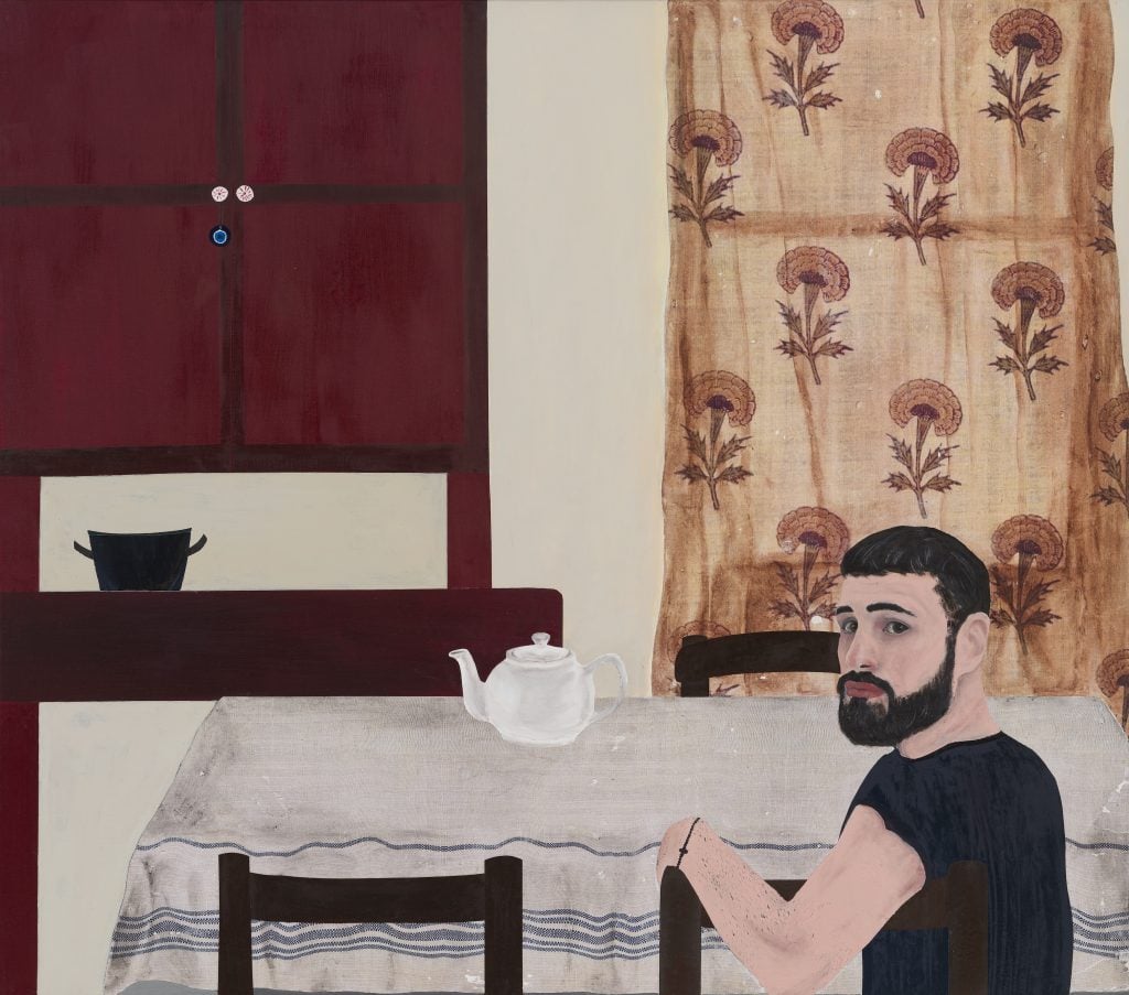 Self-portrait painting by Kiriakos Tompolidis of the artist sitting at a dining table looking over his shoulder out at the viewer and along the wall a window with a patterned curtain covering it and a doored chest with a tiny evil eye charm hanging off the pull.