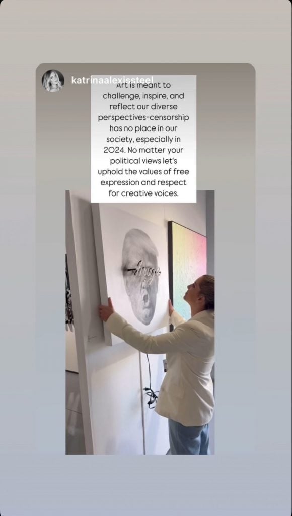 A screenshot of an Instagram story depicting a woman removing a painting of Donald Trump from a white wall, with black text contained within a square white text box superimposed above it.