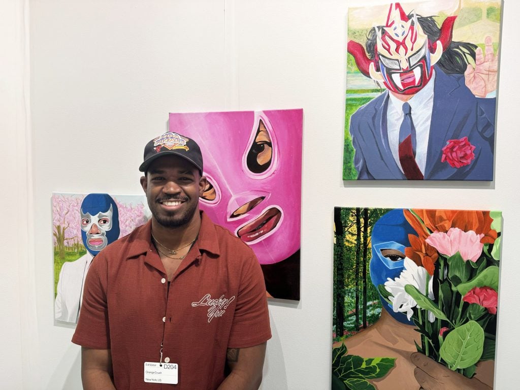 A man standing in front of paintings of wrestlers