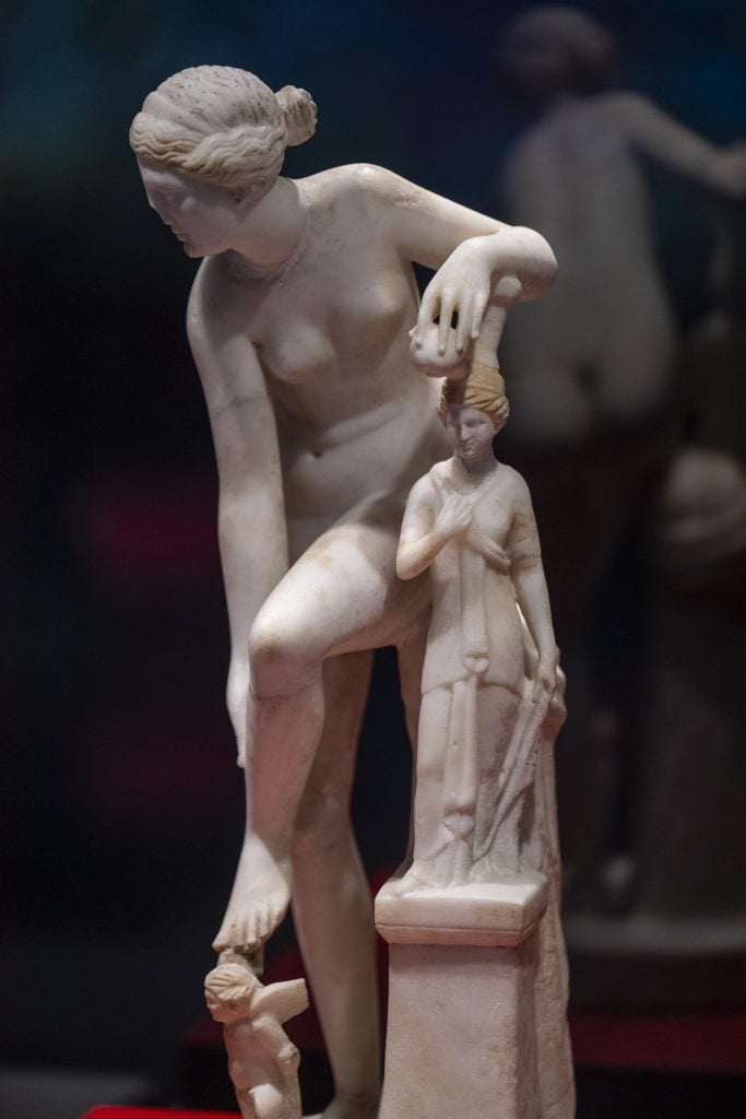 Marble statue of a woman touching a smaller figure, showcasing delicate sculptural craftsmanship.