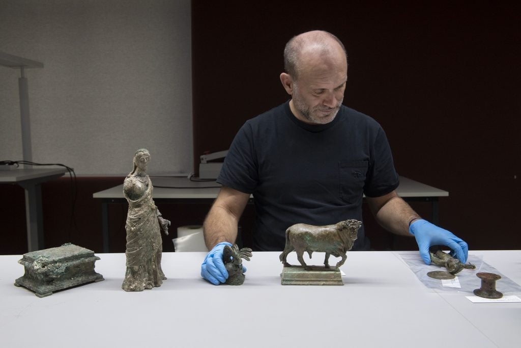 A man standing at a table with four bronze statuettes