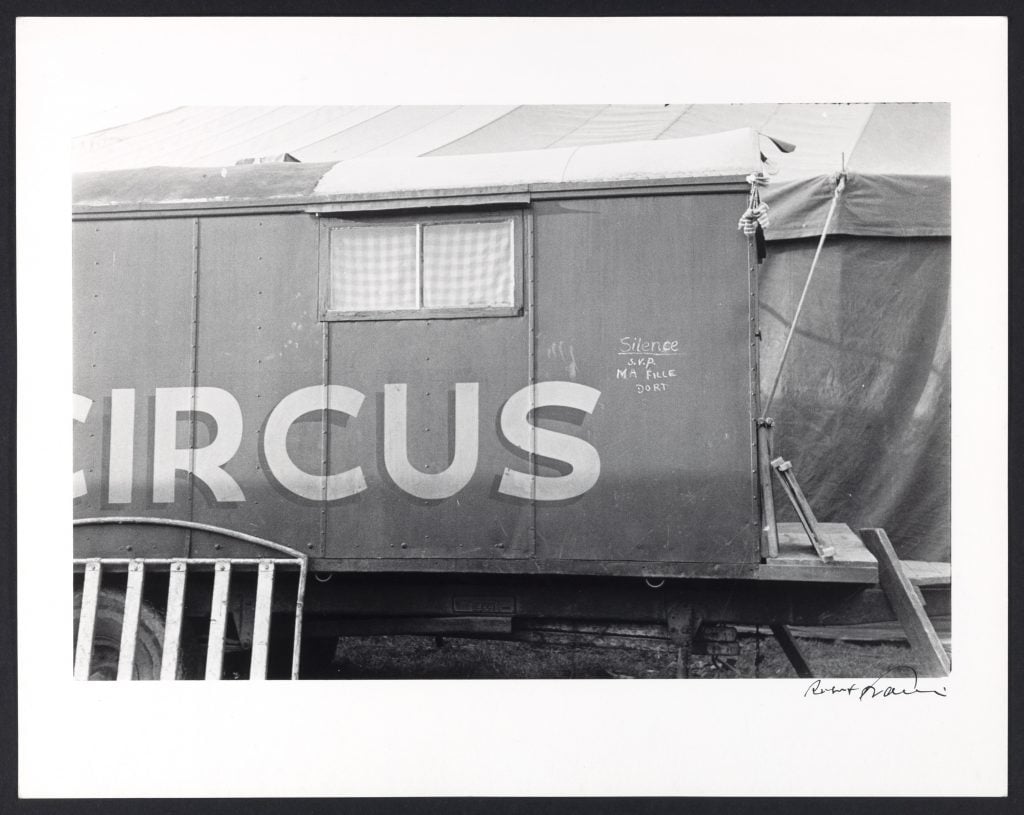 A black and white photograph depicting the exterior of a train labeled "Circus" with graffiti on it.