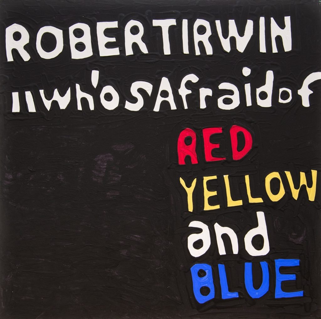 A painting that reads "Robert Irwin: who's afraid of red yellow and blue" on a black background