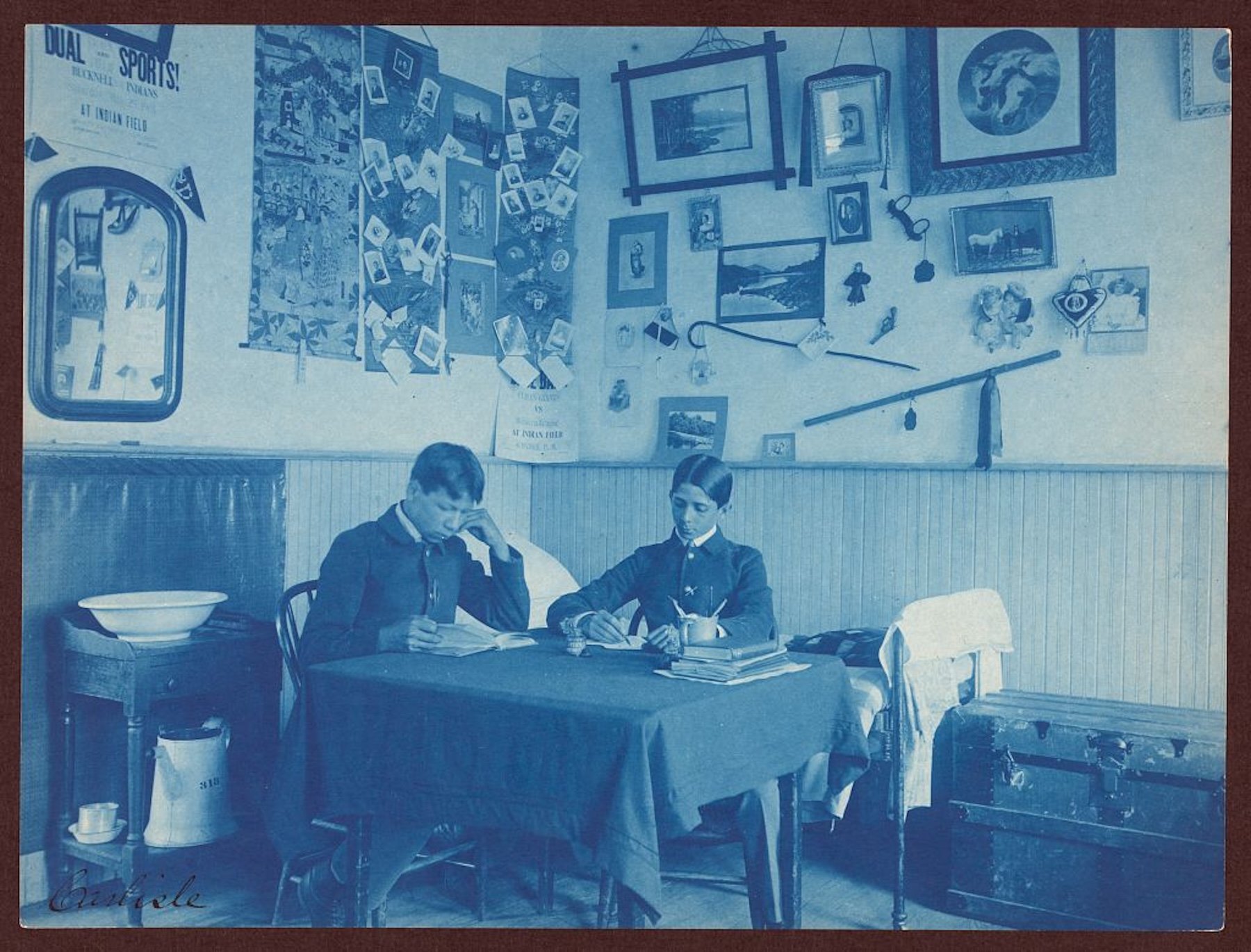 Two boys are seen studying in a dormitory room in a 1901 cyanotype photograph by Frances Benjamin Johnston