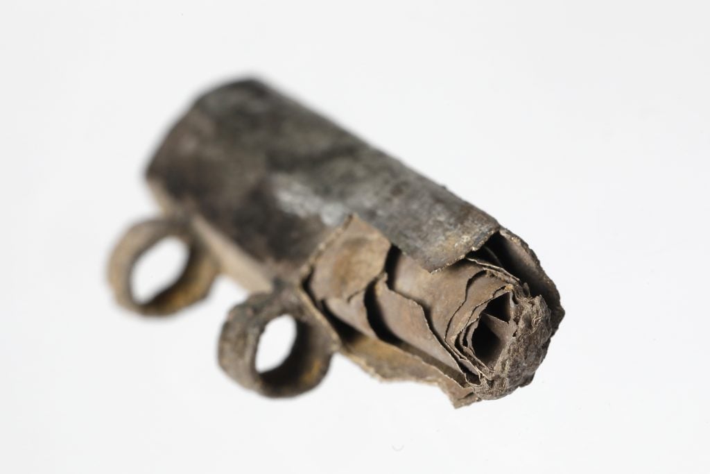 An ancient silver amulet containing a yellowing scroll