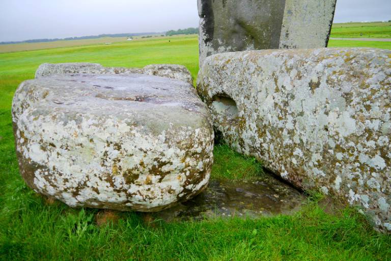 A photograph of two gray, lichen-covered slabs of rock sitting prone on green grass.