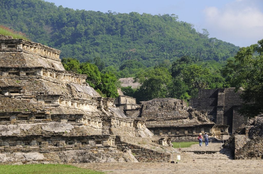 photograph of an ancient pre columbian civilization with large pyramids with forests in the background underneath a misty sky