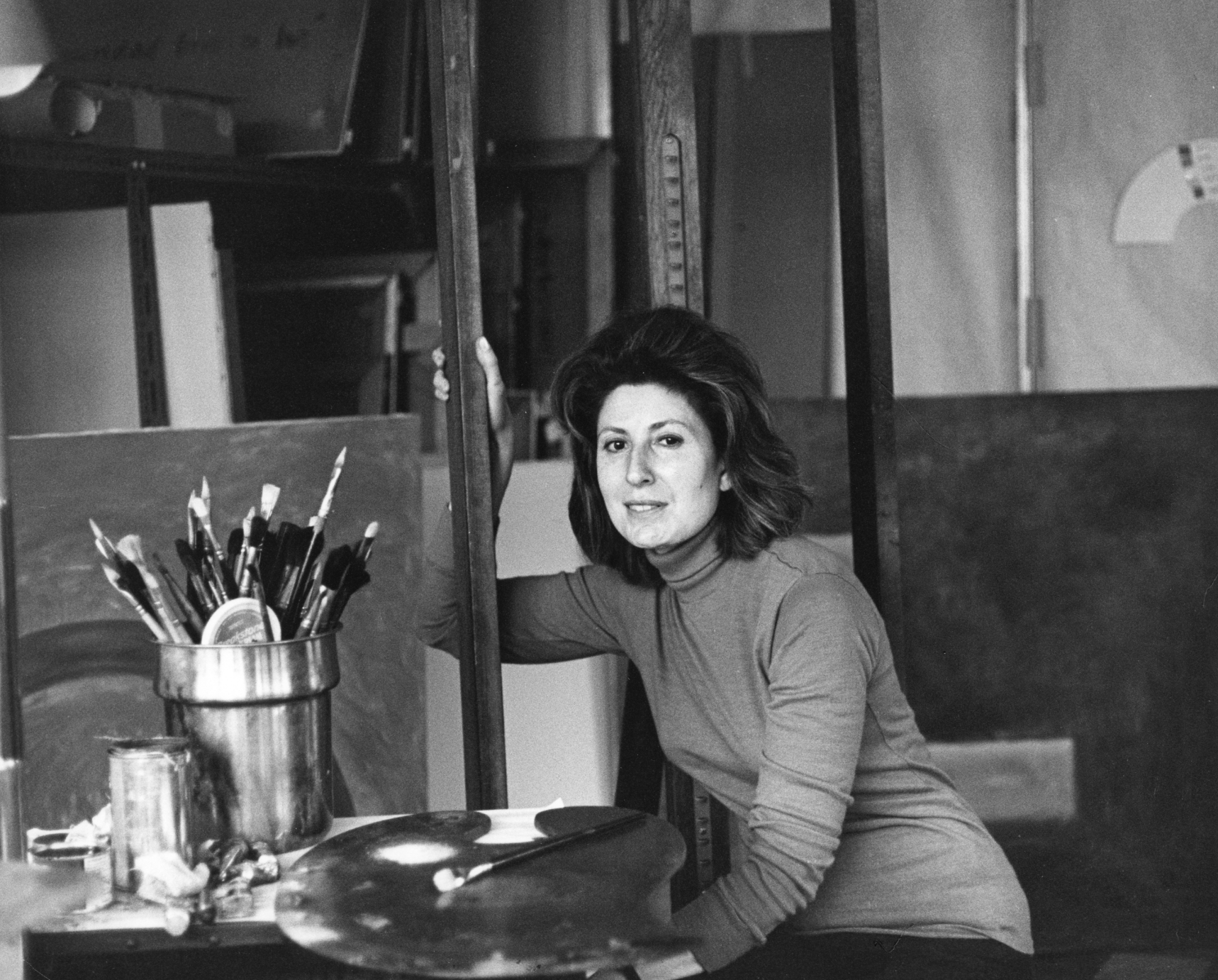 A black and white photo of a woman in an art studio