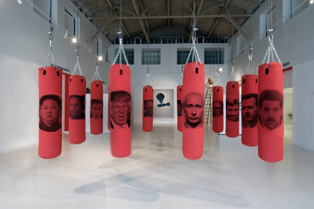 Art Palm Beach partner DIVERSEartLA installation of a series of red punching bags with silkscreen images of politician faces on them by Antuan.