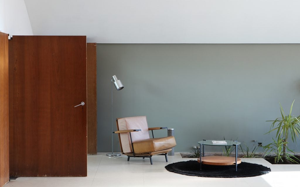 Minimalist reading corner with a leather chair, side table, and sleek lamp.