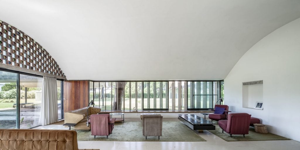 Open-plan living room at Casa Gomis, showcasing arched ceilings, colorful furniture, and expansive glass windows.