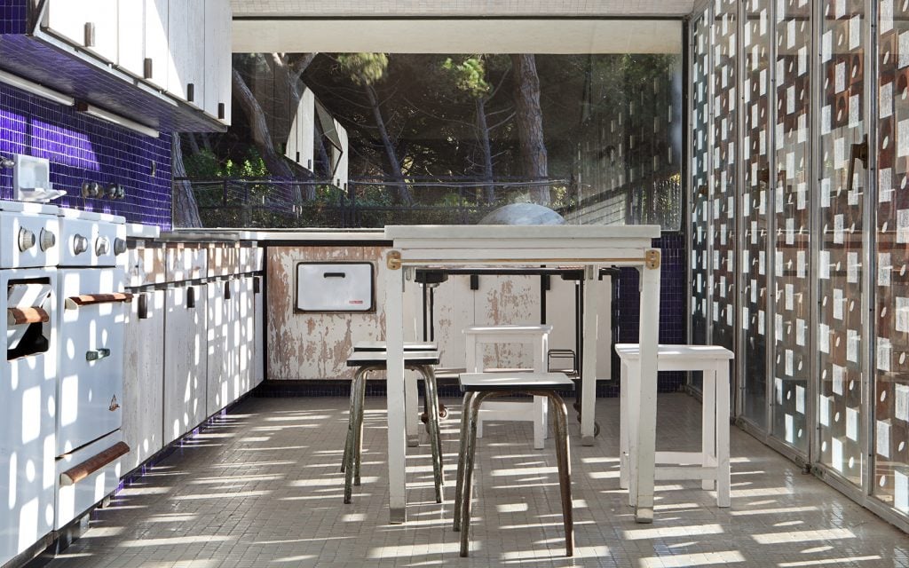 Sunlit kitchen in Casa Gomis with geometric patterns, vintage appliances, and modernist white furniture.