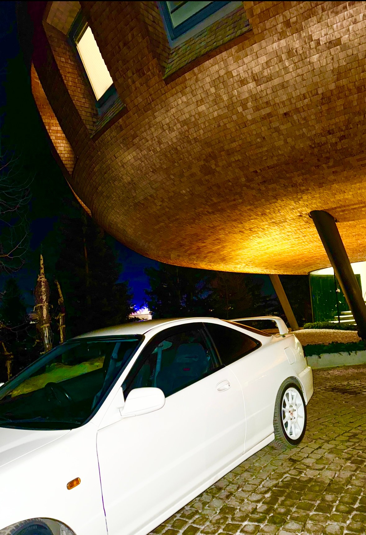 A car parked beneath a curvaceous building