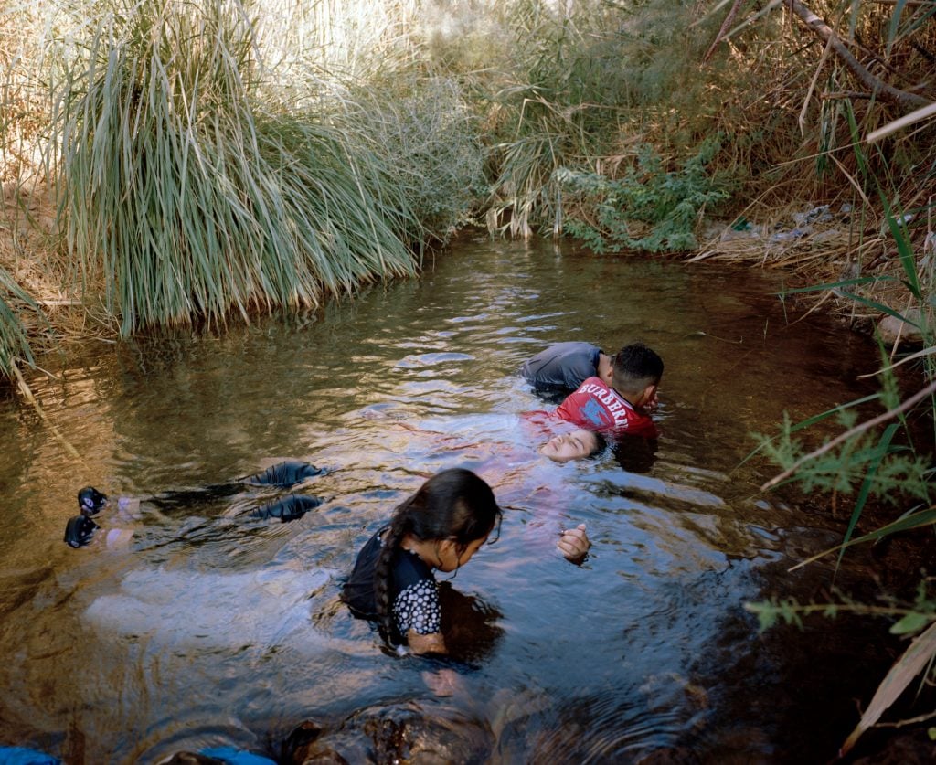 a photo of children playing and swimming in a clear watered pond