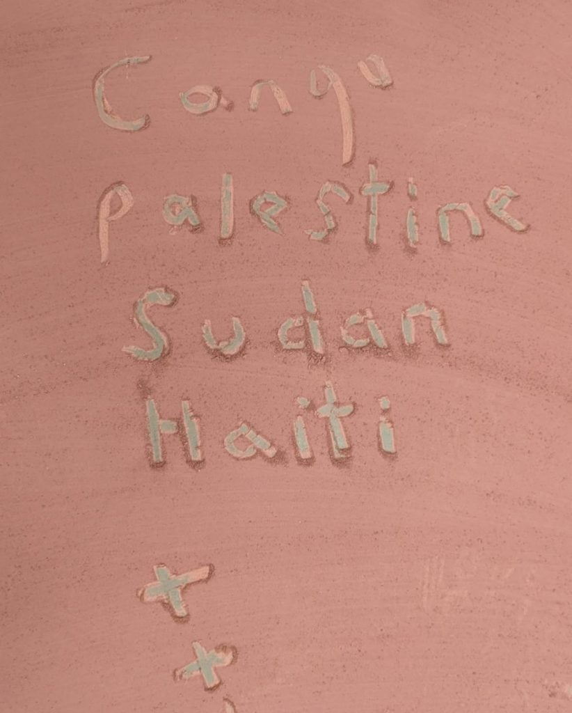 the words "congo, palestine, sudan, haiti + + +" written by hand into the surface of clay