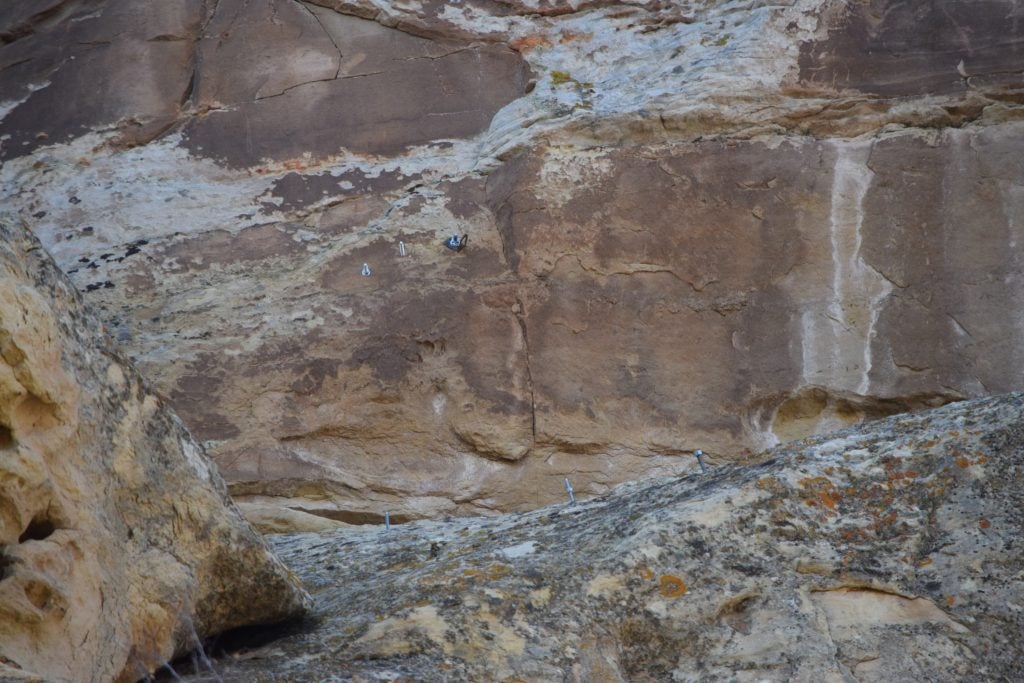 Climbing bolts are pictured in the rock face near ancient petroglyphs in Utah