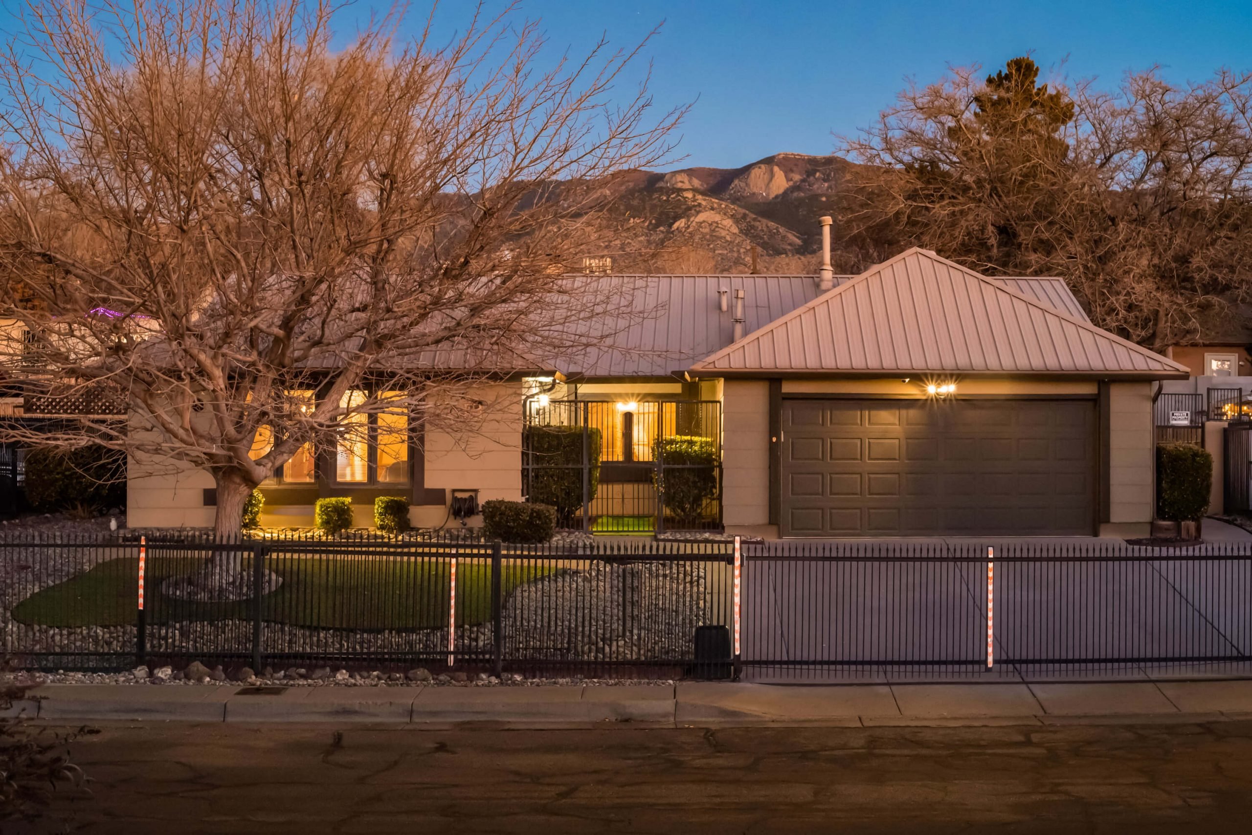 The Breaking Bad house with a modest exterior, metal garage, and evening lights illuminating its facade.