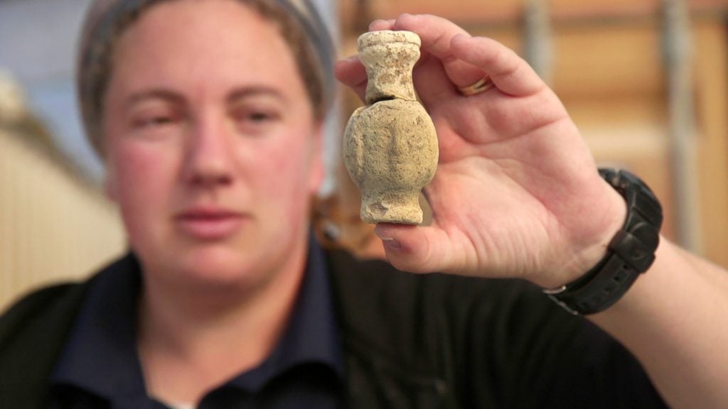 An image of Someone holding up an artifact from the site of a former Byzantine monastery in Israel.