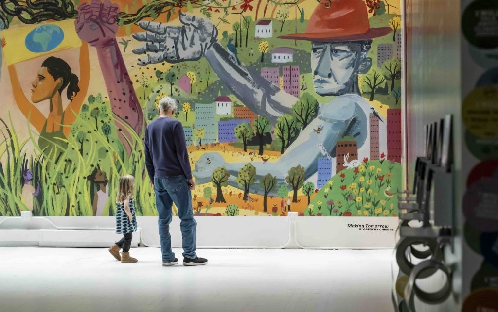 Visitors stand before a large painted mural