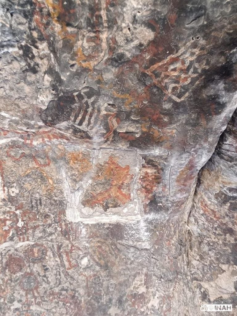 Damage to the cave wall where a panel of ancient art sits is pictured.