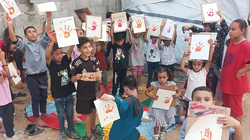 An image of Palestinian children in Gaza with art that they made.