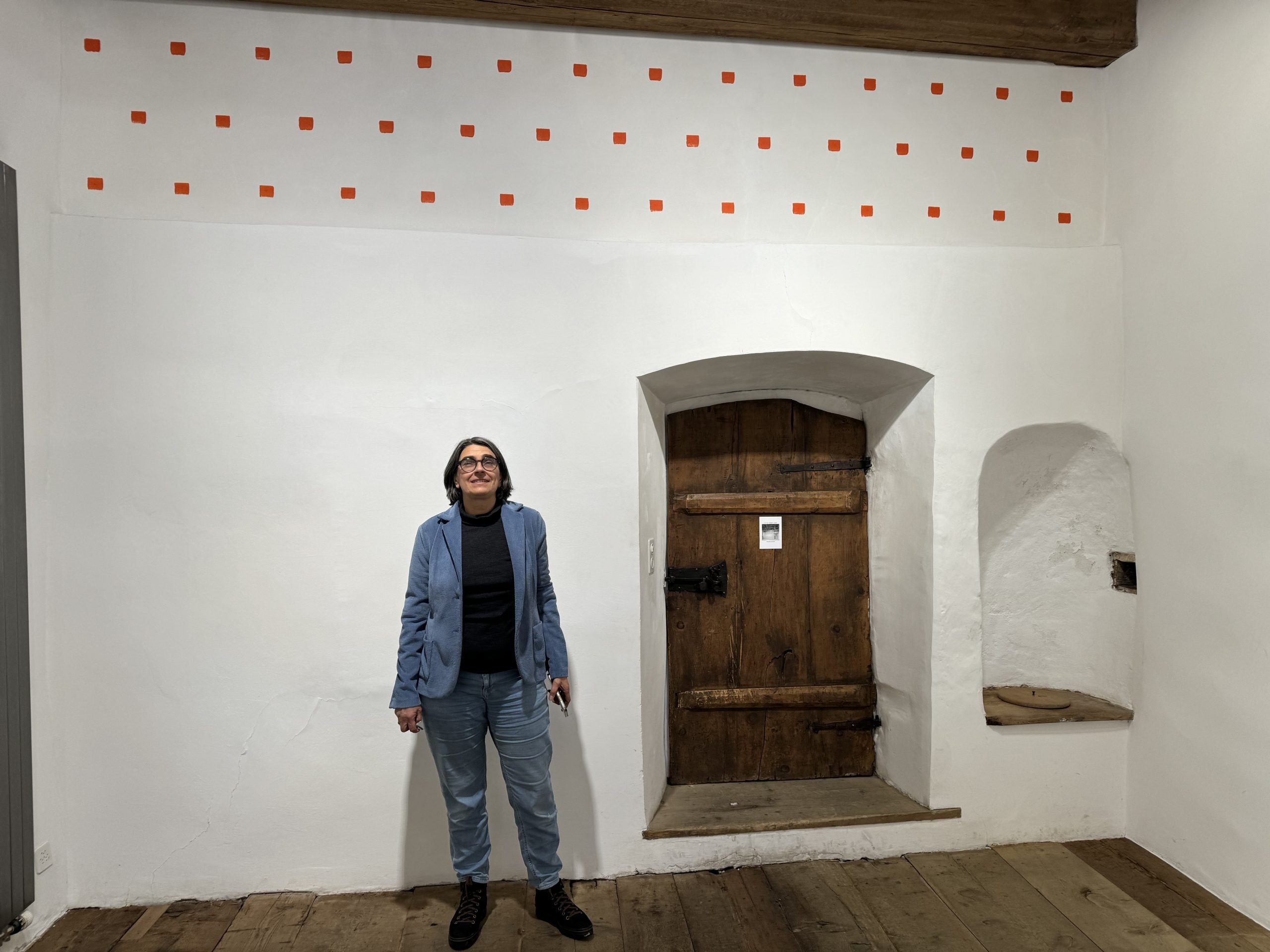 A person stands beneath a painting of dots