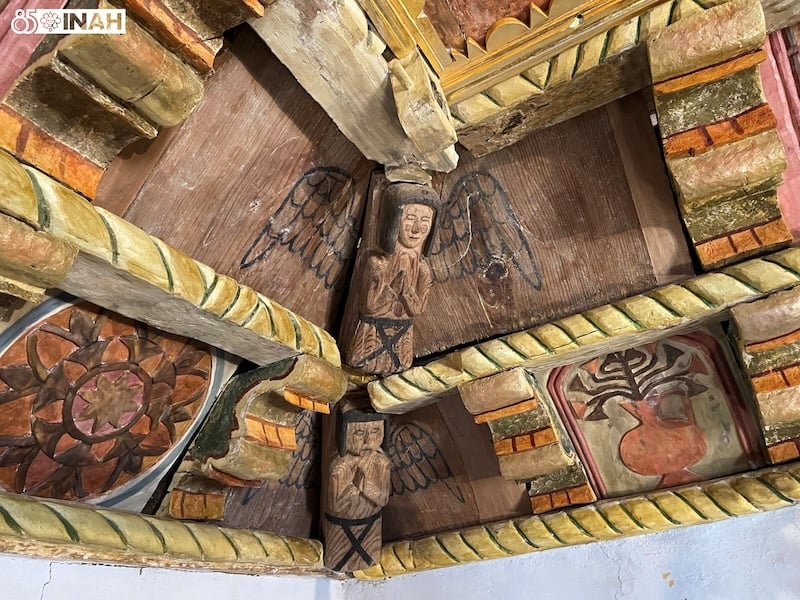 Close-up of hand-carved wooden angel figures with painted details on a church ceiling structure.