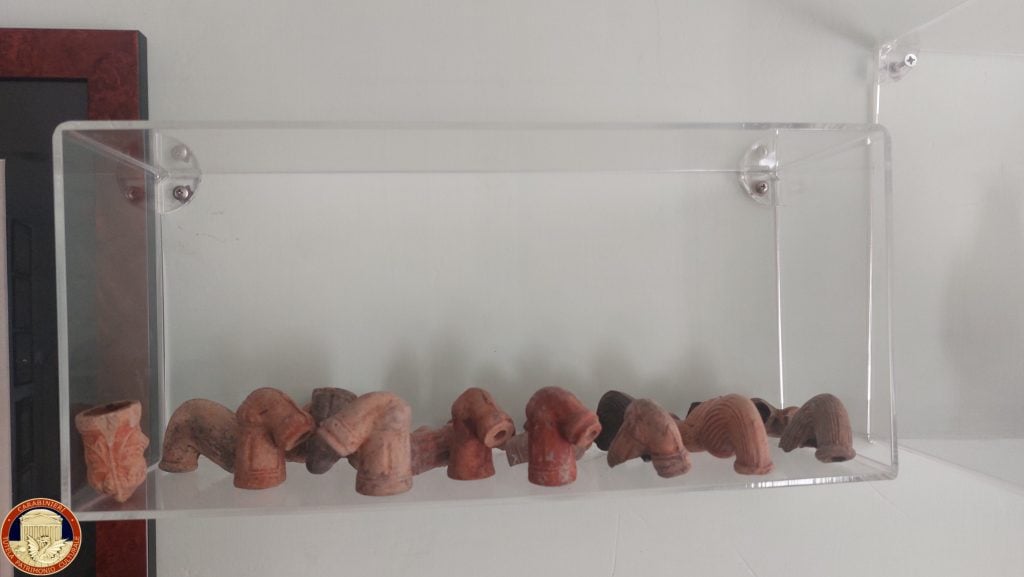 pieces of ancient terracotta pipe are arranged in a glass display cabinet 