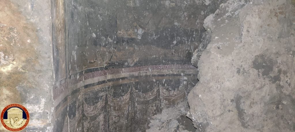 amid some old pieces of stone emerges an semicircular frescoed apse that is very dirty but clearly belongs to an old buried structure like a church