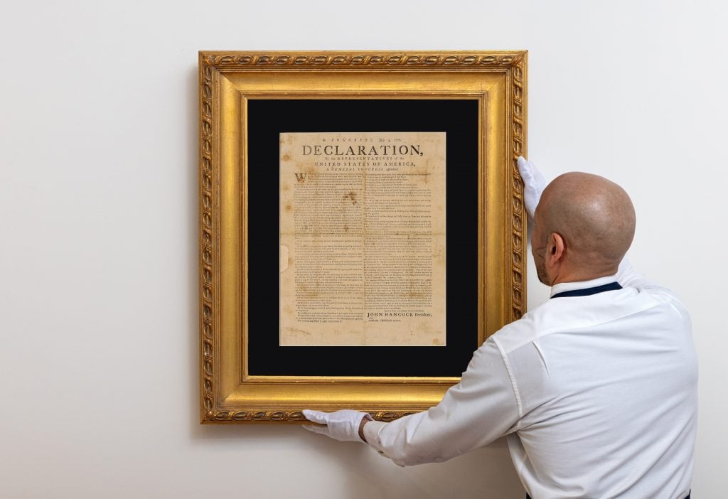 An art handler displays a copy of the Declaration of Independence