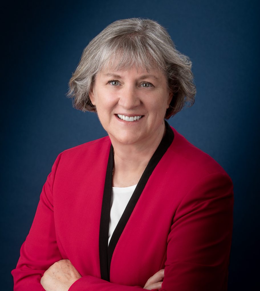 A woman, Debra Townsley, president of Albright College, smiles for the camera in a red suit jacket