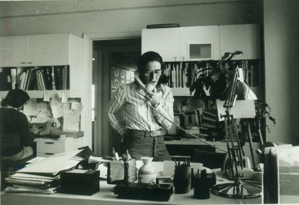 a woman, Doris Chanin Freedman, talks on the phone while standing in an office