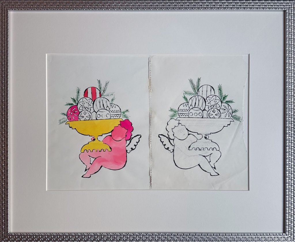 Framed artwork featuring two mirrored ink line drawings of a cherub holding a pedestal bowl overflowing with decorative ornaments and pine sprigs. The left image is partially hand-colored with vibrant pinks, yellows, reds, and greens, while the right image remains in black and white. Both drawings reflect Andy Warhol’s blotted line technique, with slight imperfections that highlight the hand-transferred process. Set in a wide white mat and textured silver frame.