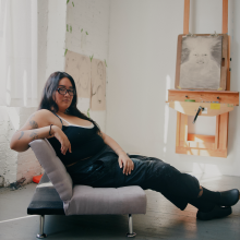 A photograph of an asian woman sitting on a chair in an art studio