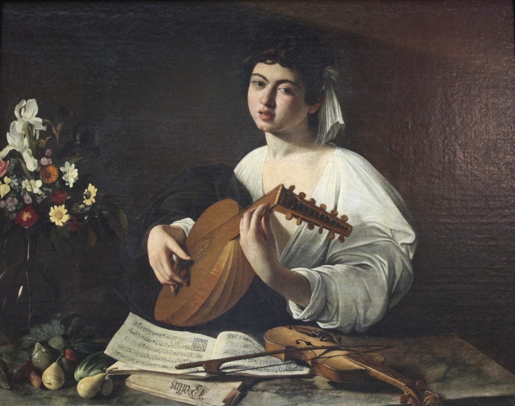 Young musician in white robe plays lute, surrounded by sheet music, violin, fruit, and flowers.