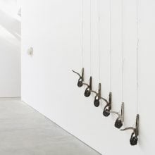 A light-filled gallery shows small artworks on the wall, with trees outside the window.