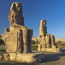 two giant statues of Egyptian pharaoh on blue sky background