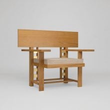 Minimalist wooden armchair with geometric design and beige cushion, modern functional furniture.