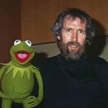 Jim Henson with bushy brown beard his cartoonish green puppet frog