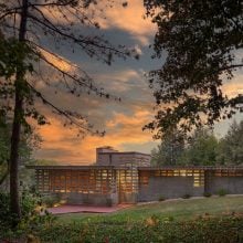 Exterior view of the Frank Lloyd Wright–designed Kalil House at sunset, with patterned concrete blocks glowing warmly.