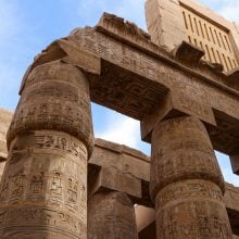 Carved sandstone columns with hieroglyphs at the Great Hypostyle Hall of Karnak Temple in Luxor, Egypt.