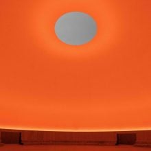 a view of an orange room with a hole to the sky James Turrell