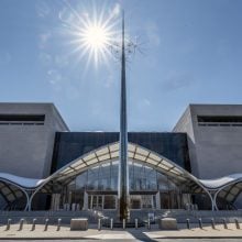 The sun shines above the Smithsonian National Air and Space Museum’s sleek glass entrance and metallic spire.