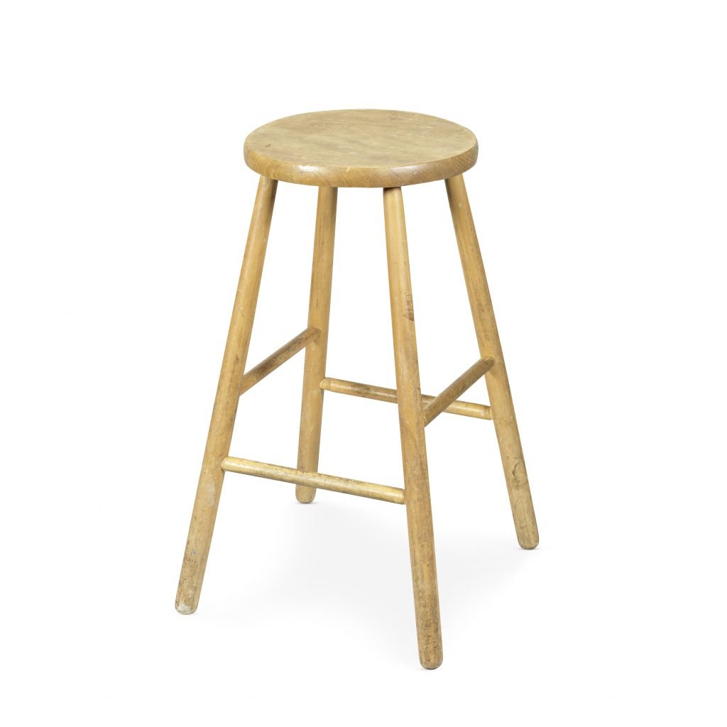 Worn wooden studio stool with round seat and splayed legs, once used by David Bowie.