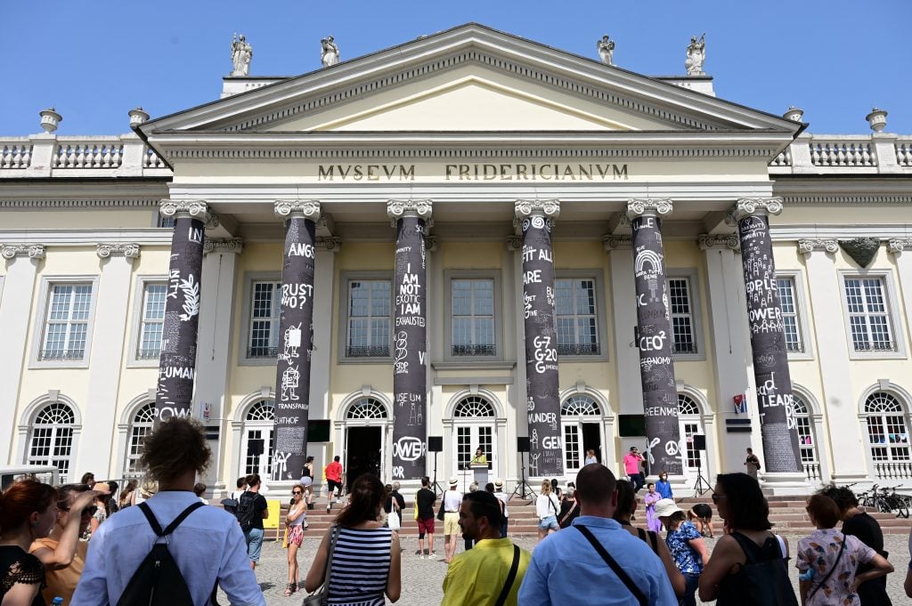 a crowd stands in front of a large building with columns